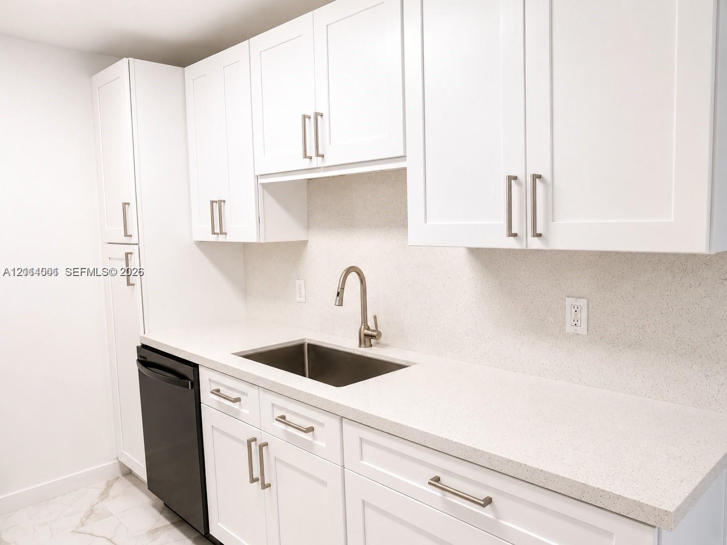 Kitchen featuring white shaker-style cabinetry, solid-surface countertops, a stainless steel undermount sink, brushed nickel faucet, and a black dishwasher