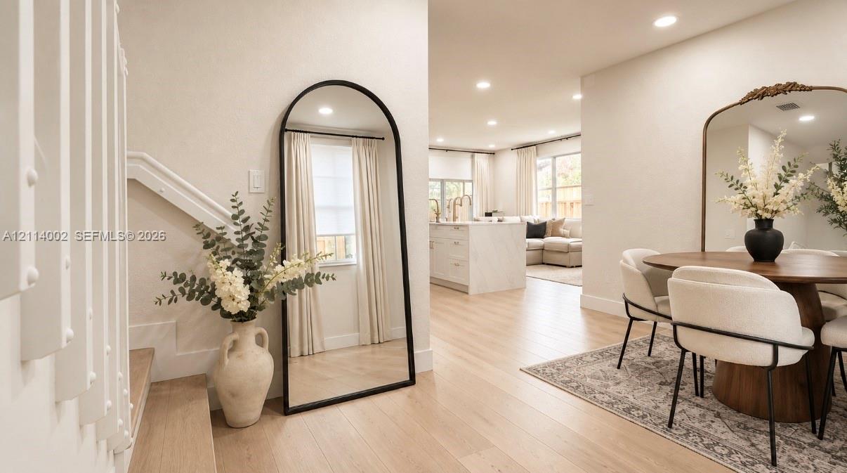Open floor plan featuring wood-finish flooring, recessed lighting, and a central island with stone-finish waterfall countertop