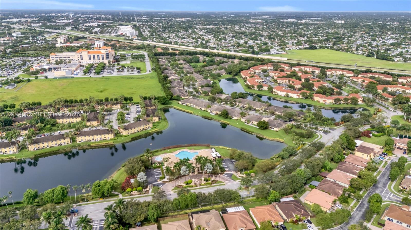 Aerial perspective of community featuring a centralized swimming pool, extensive water frontage, and manicured landscaping