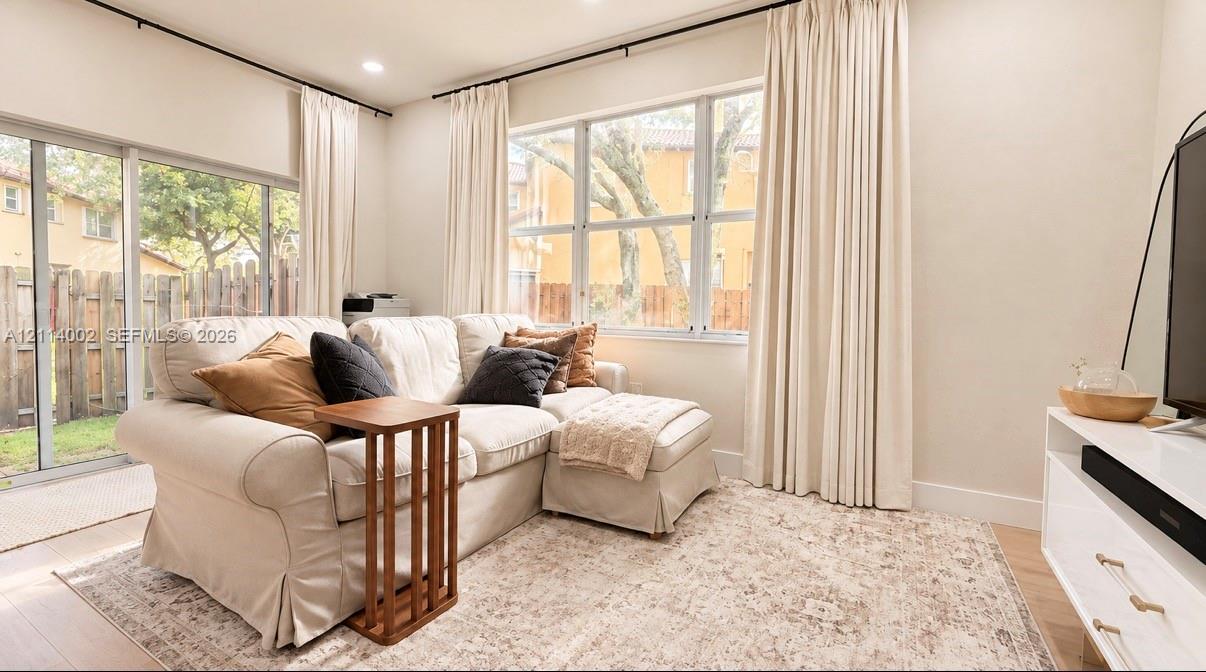 Living space featuring floor-to-ceiling windows, sliding glass door, recessed lighting, and light-toned wood-finish flooring