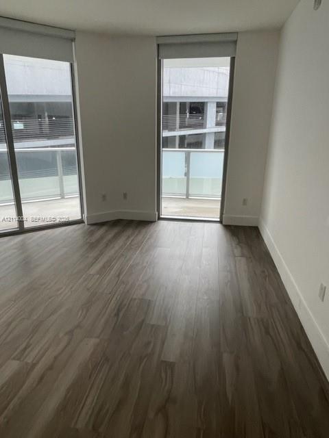 Floor-to-ceiling windows, wood-finish flooring, and access to a balcony with metal railing Floor-to-ceiling windows, wood-finish flooring, and access to a balcony with metal railing