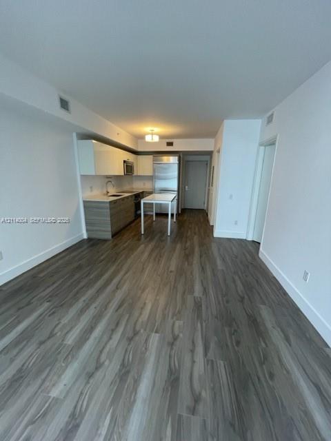 Kitchen featuring two-tone cabinetry, stainless steel refrigerator, stone countertops, and wood-finish flooring Kitchen featuring two-tone cabinetry, stainless steel refrigerator, stone countertops, and wood-finish flooring