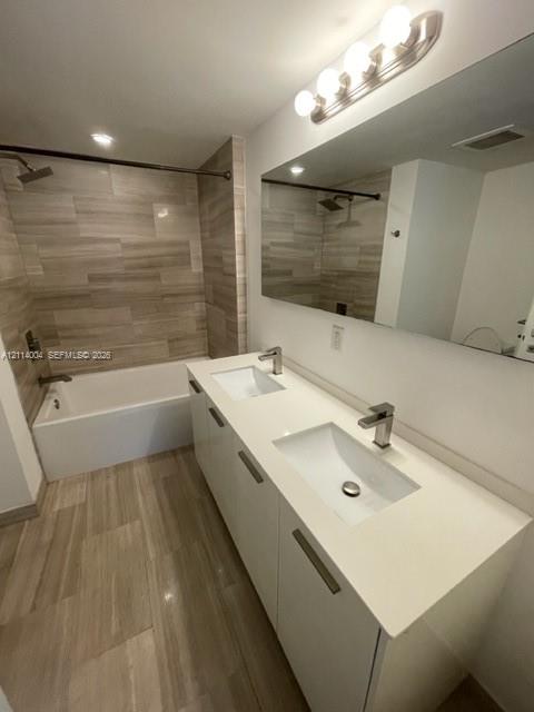 Dual-sink vanity with white cabinetry, solid surface countertop, and brushed metal hardware, complemented by horizontal tile flooring and matching wall tile in the tub surround Dual-sink vanity with white cabinetry, solid surface countertop, and brushed metal hardware, complemented by horizontal tile flooring and matching wall tile in the tub surround
