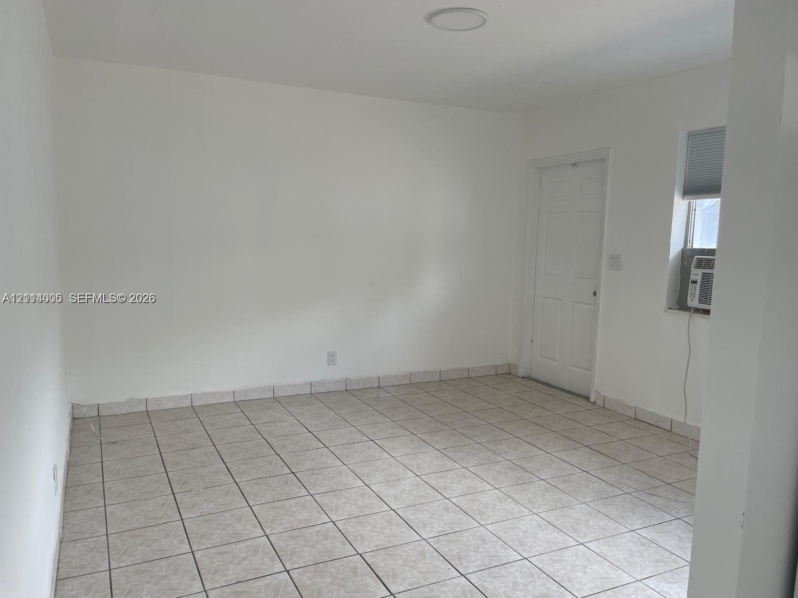 Neutral interior featuring ceramic tile flooring, a six-panel door, and a single-hung window with a recessed mounting