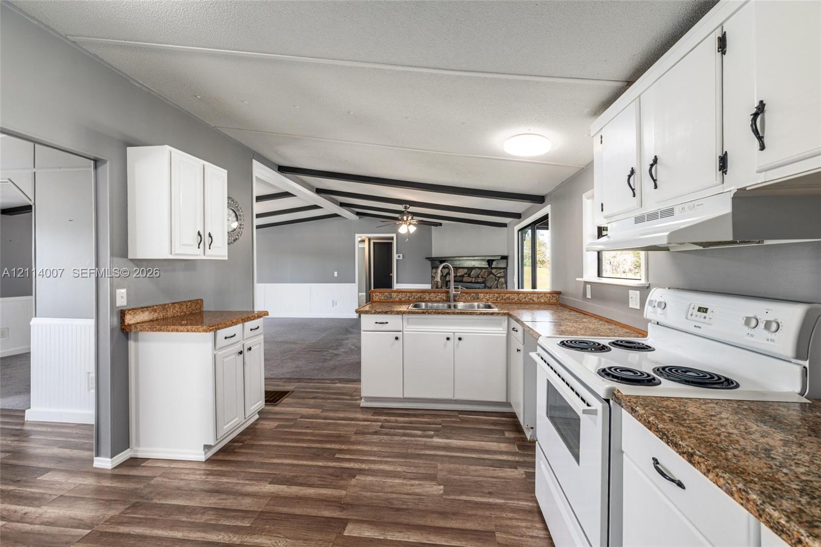 Kitchen featuring white cabinetry, stone-finish countertops, wood-finish flooring, and a stainless steel sink with a high-arch faucet