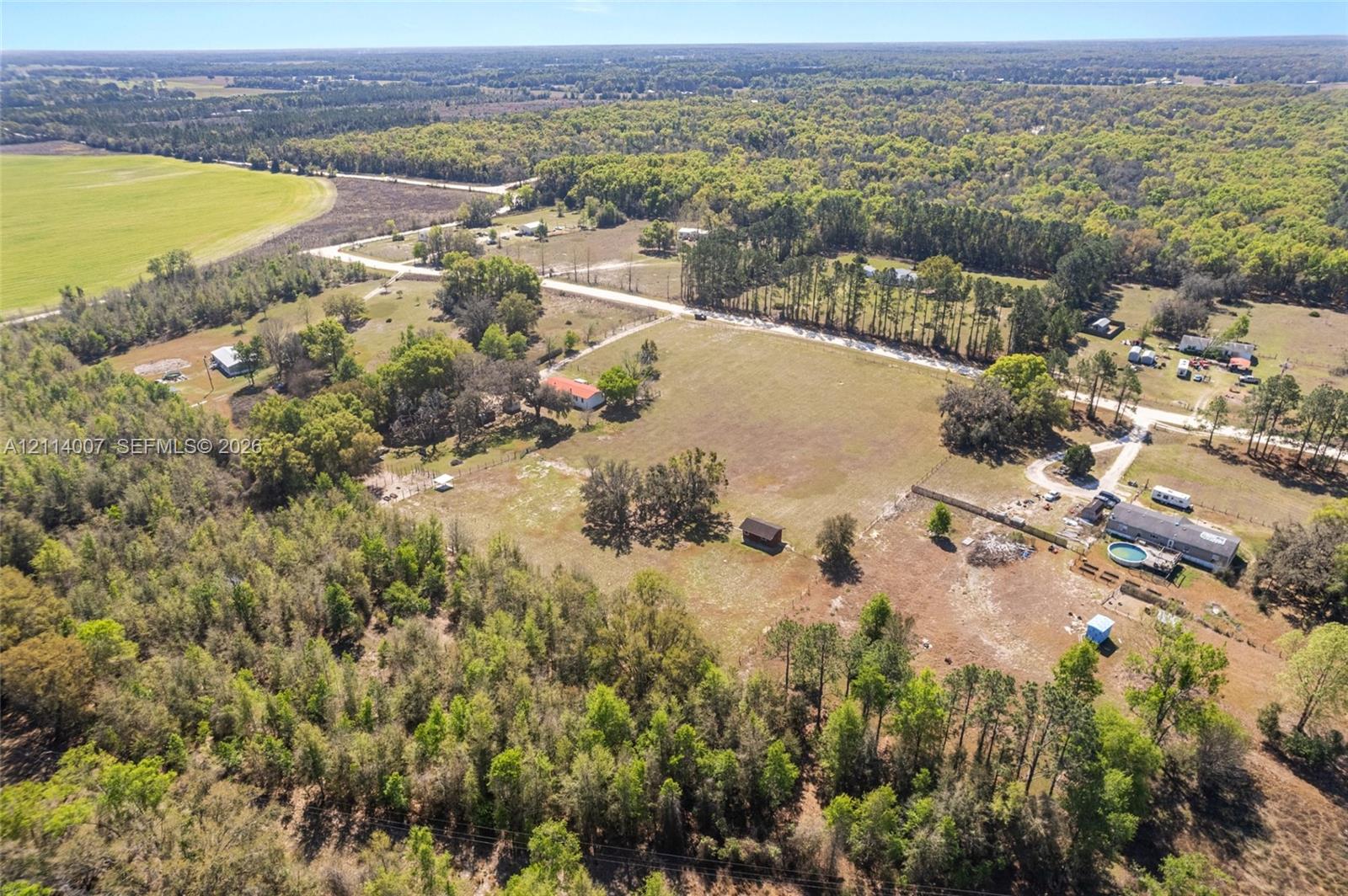 Expansive acreage featuring mature tree lines, open pastoral land, and a paved road frontage