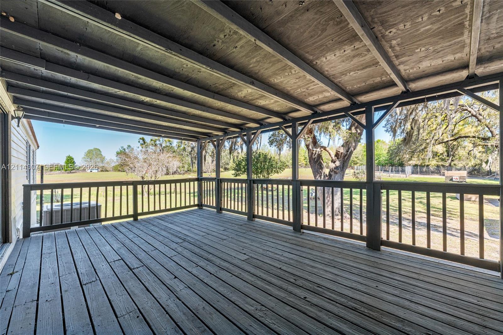 Covered deck featuring wood-finish flooring, an exposed beam ceiling, and surrounding wooden railing