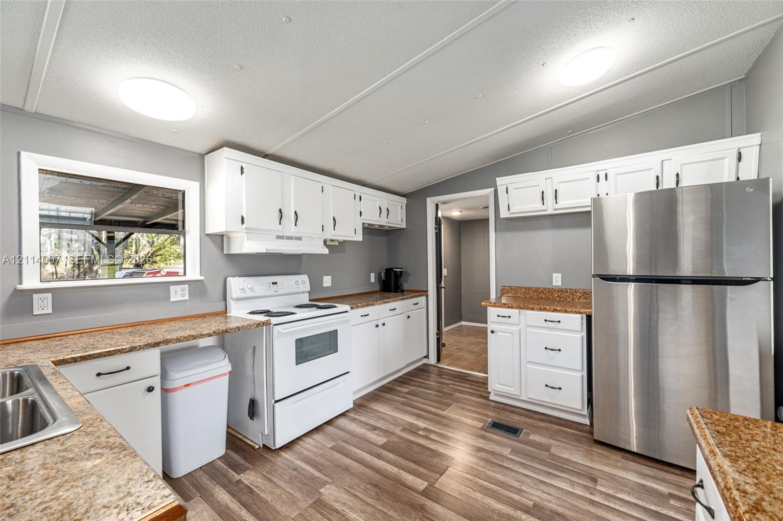 Kitchen featuring white cabinetry, stone-finish countertops, stainless steel refrigerator, white freestanding range, and wood-finish flooring