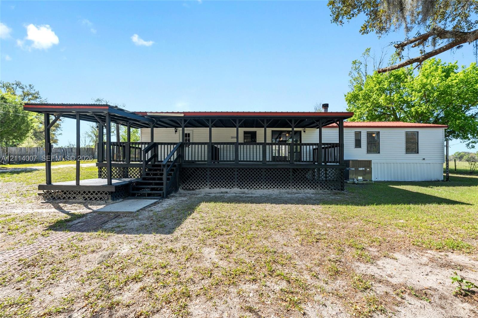 Exterior featuring a sprawling covered deck with dark wooden railings, a metal roof, and lattice skirting