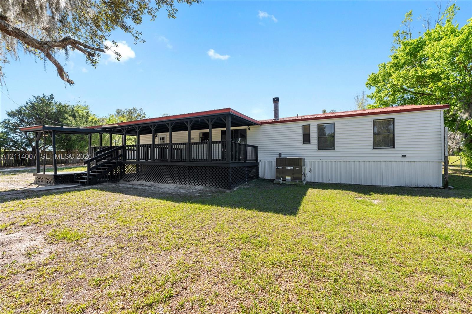 Exterior featuring horizontal siding, a covered wraparound wood deck with lattice skirting, and a metal roof