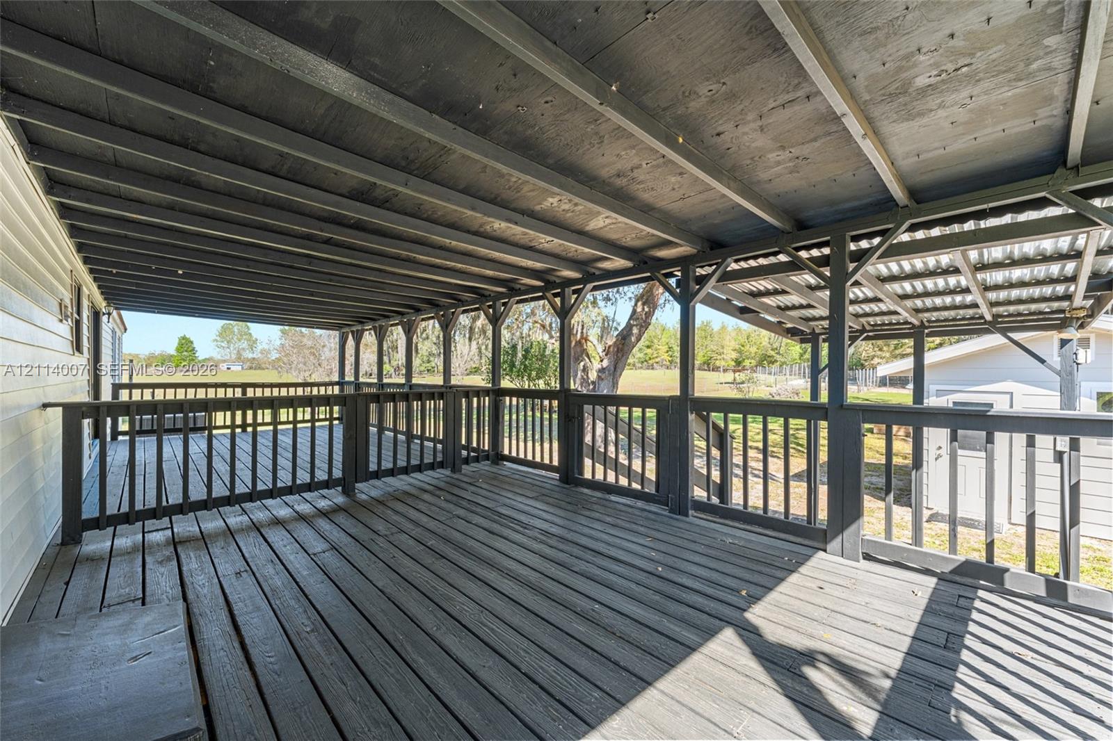 Covered outdoor deck featuring wood decking, a dark-toned timber frame structure, and black painted wooden balustrades