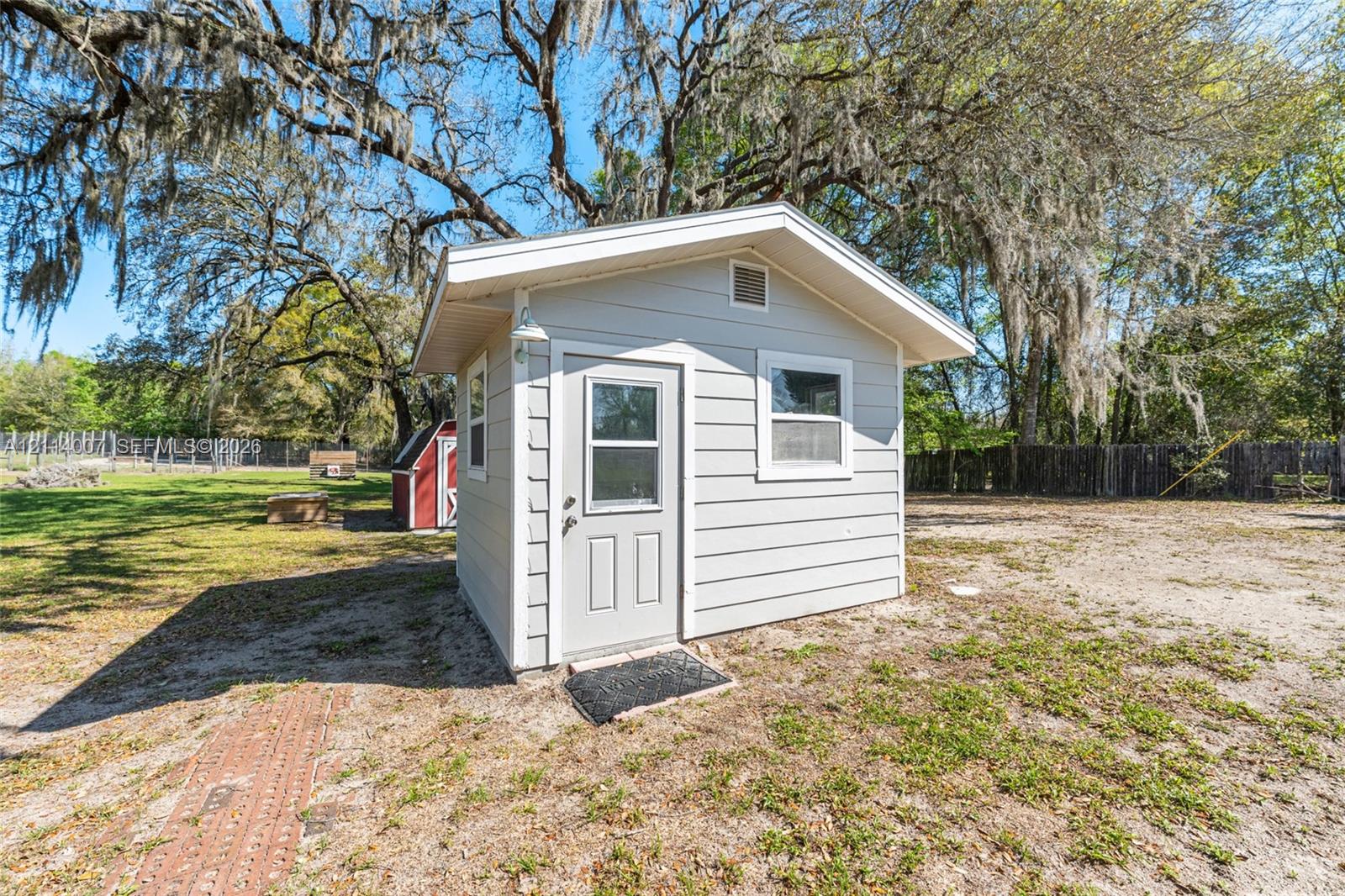 Detached storage shed featuring light-colored horizontal siding, a gabled roof, and two windows