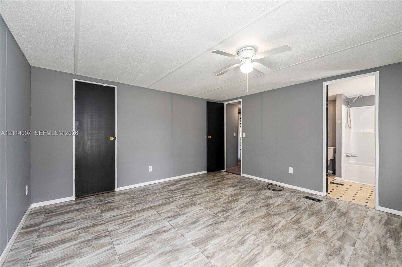 Interior room featuring wood-finish flooring, two solid-core doors, and a ceiling-mounted light fixture with integrated fan