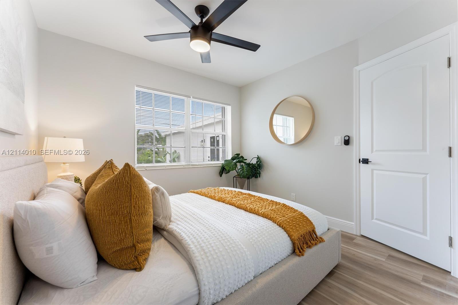 Neutral wall tones paired with wood-finish flooring, multi-pane window, matte black ceiling fan with integrated lighting, and white interior door featuring matte black hardware