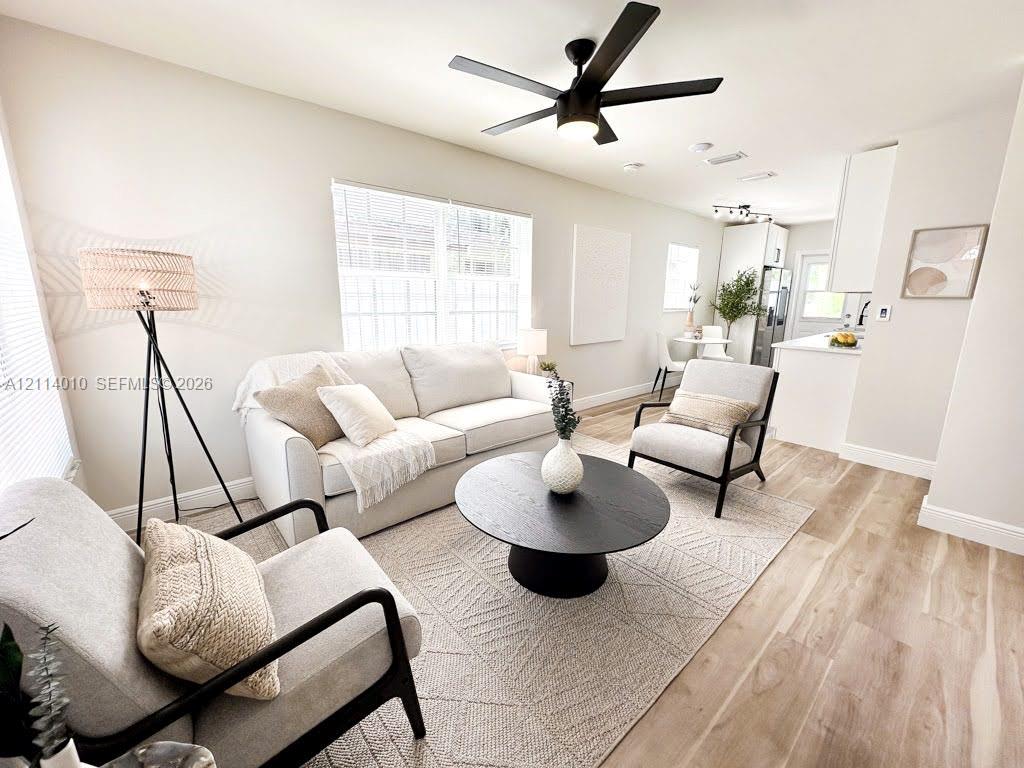 Open-concept interior featuring light wood-finish flooring, recessed lighting, matte black ceiling fan with integrated lighting, and white cabinetry