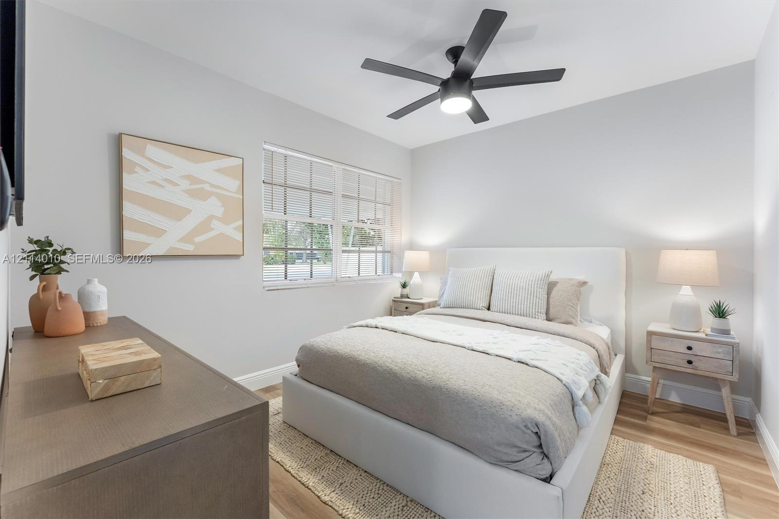 Multi-pane window, wood-finish flooring, and matte black five-blade ceiling fan with integrated lighting