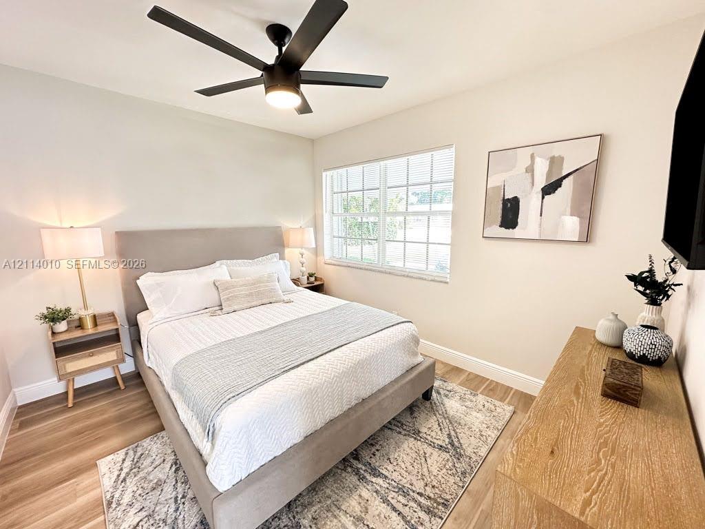Neutral interior featuring wood-finish flooring, a multi-pane window, and a matte black ceiling fan with an integrated light fixture