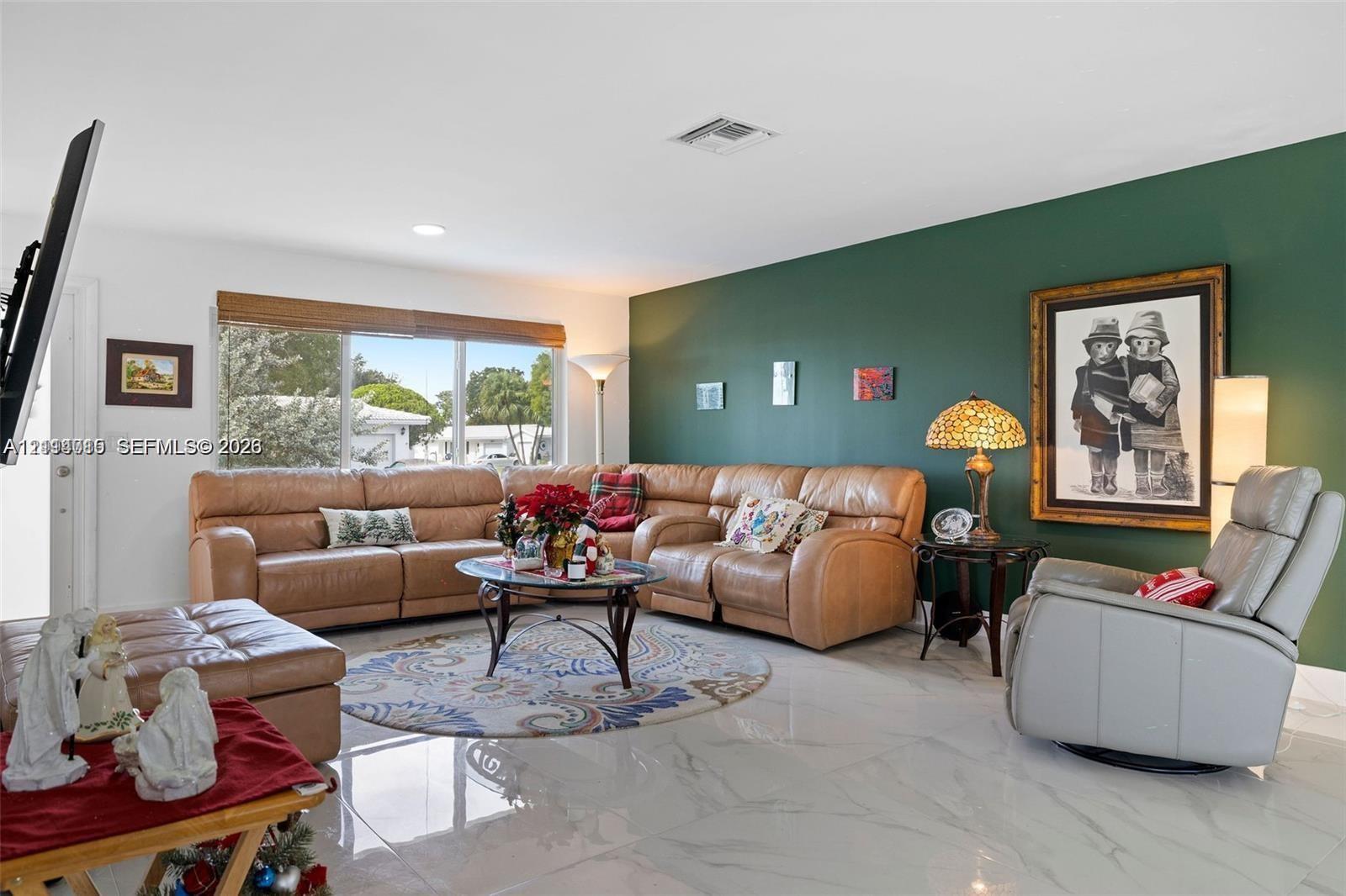 Large-format light-toned tile flooring, deep green accent wall, and expansive window with natural lighting