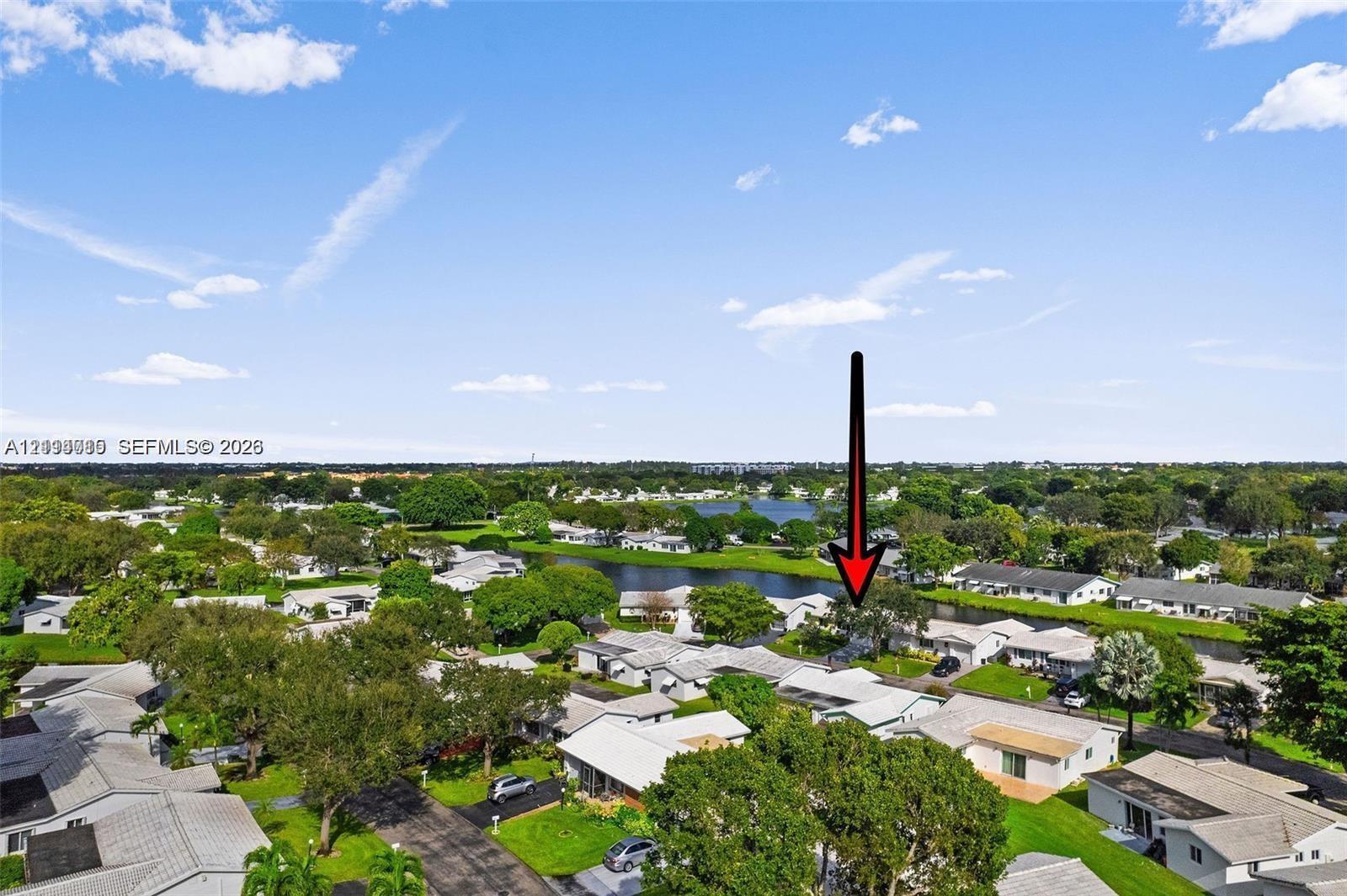 Aerial perspective of a residential property featuring a pitched roofline, paved driveway, and established landscaping