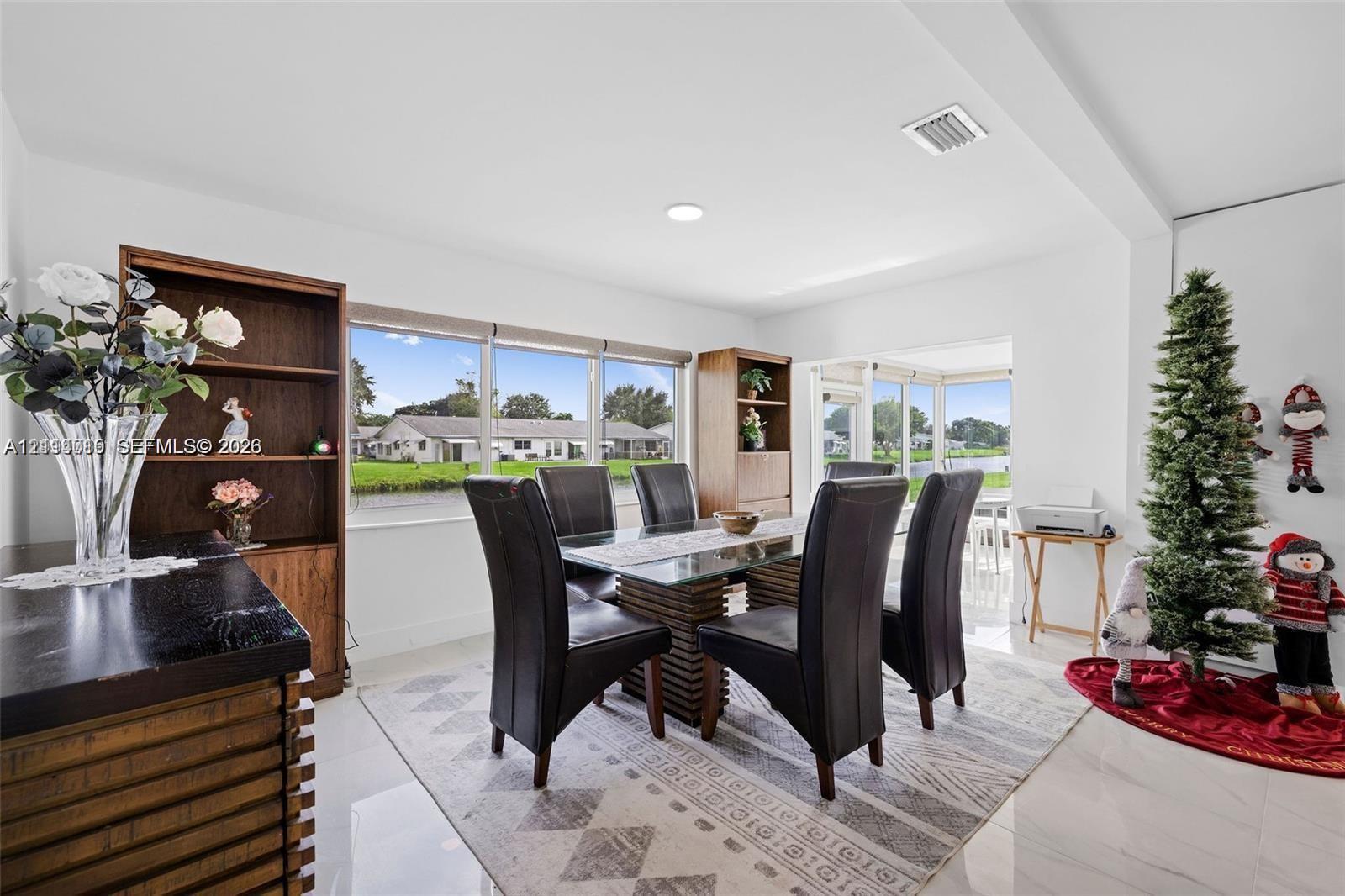 Bright dining area featuring large windows with exterior water exposure, polished tile flooring, and integrated wood-finish cabinetry