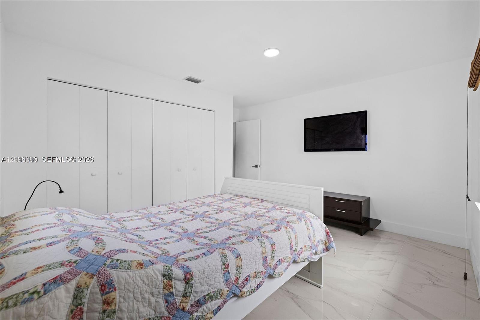 Neutral-toned stone-finish flooring and large wall-to-wall closet featuring white panel doors