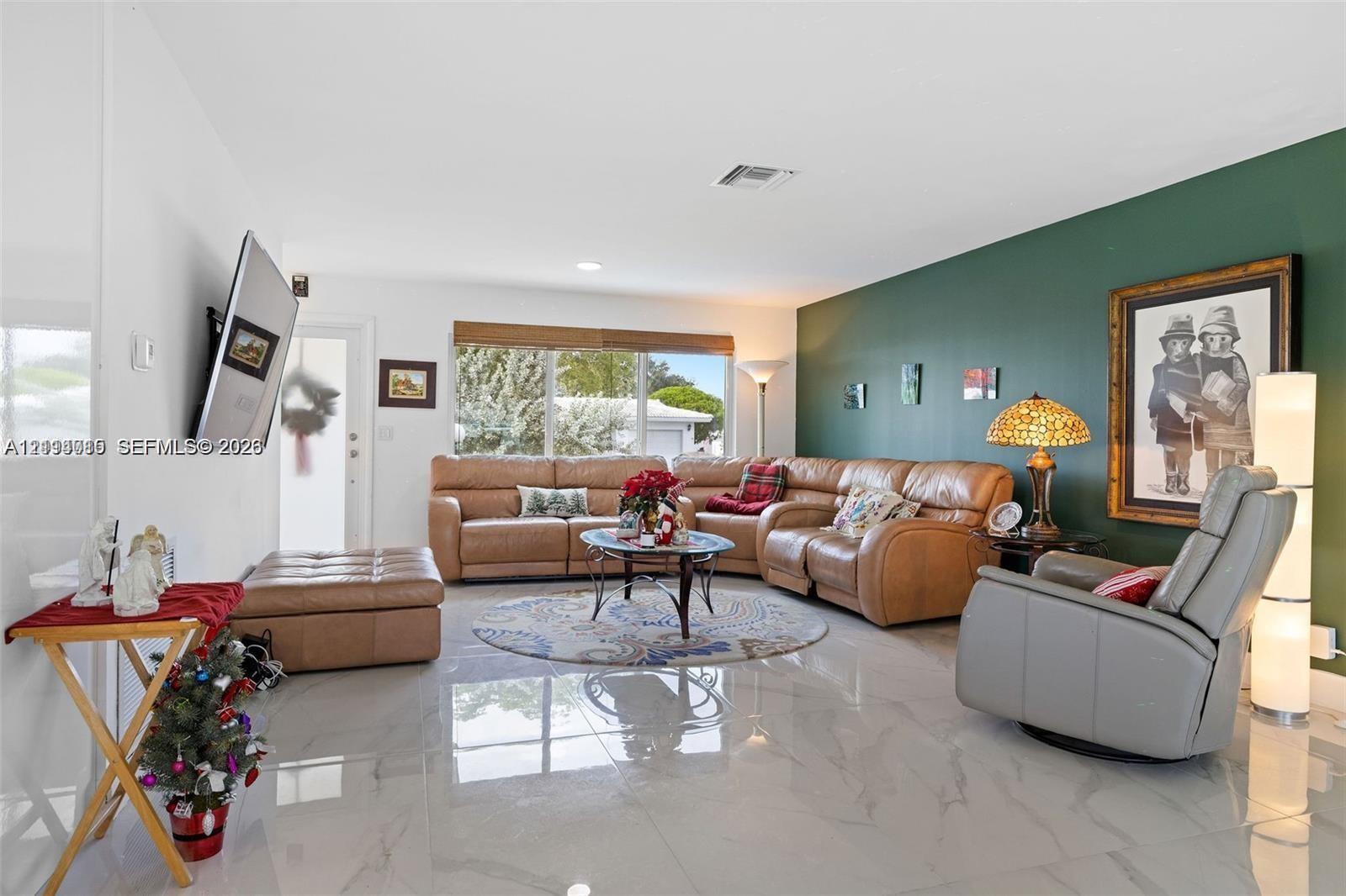 Spacious interior featuring large-format polished tile flooring, recessed ceiling lighting, and a prominent accent wall