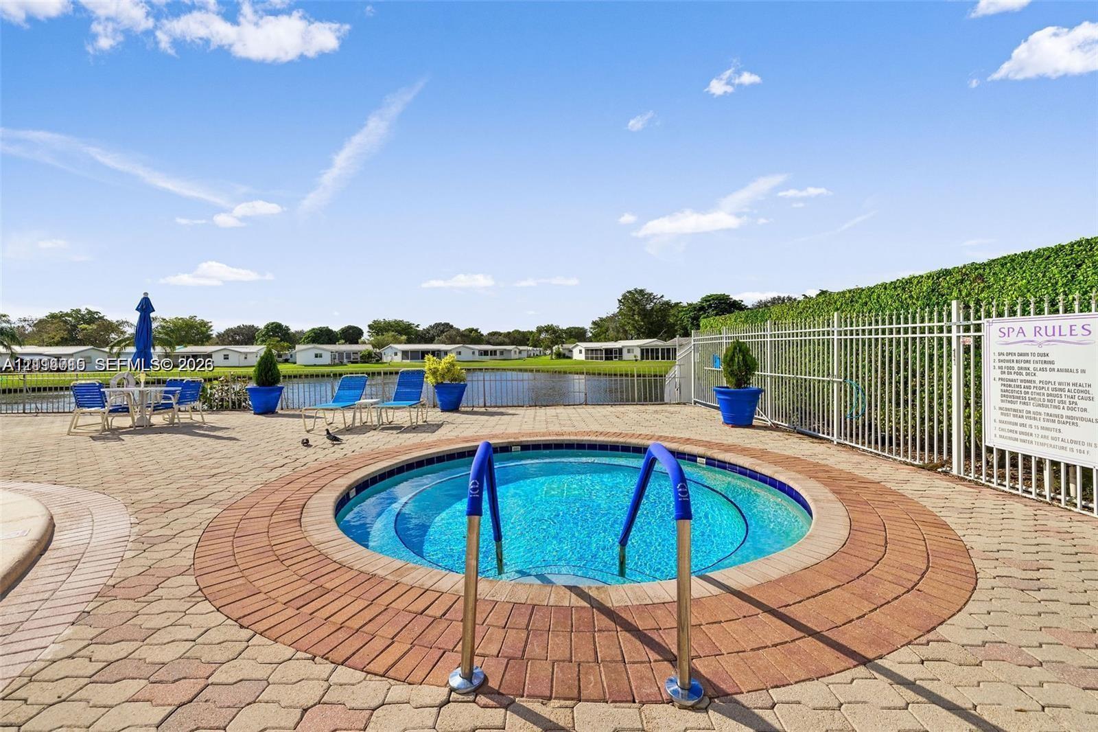 In-ground circular spa featuring a paver stone deck, metal safety fencing, and water-facing orientation