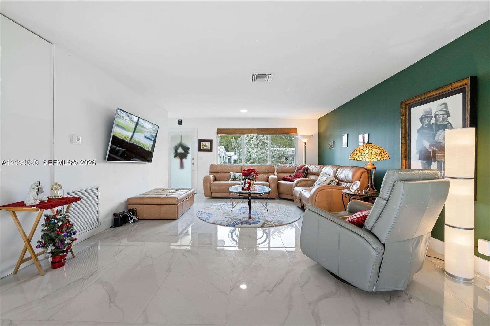Large-format tile flooring, accent wall, and expansive window with horizontal blind