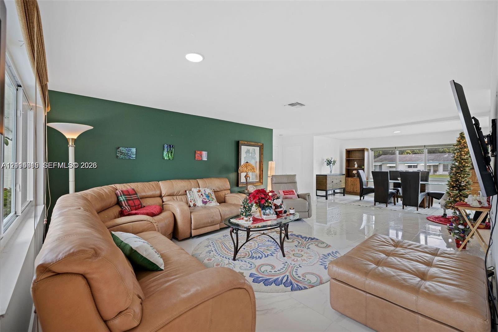 Open living area featuring polished tile flooring, recessed lighting, and a prominent green accent wall
