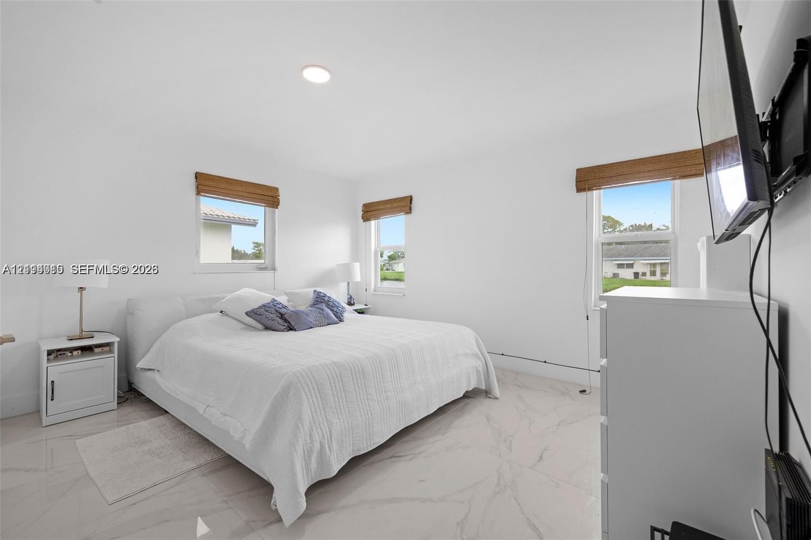 Bright room featuring large-format tile flooring, recessed lighting, and multiple windows with woven wood shades