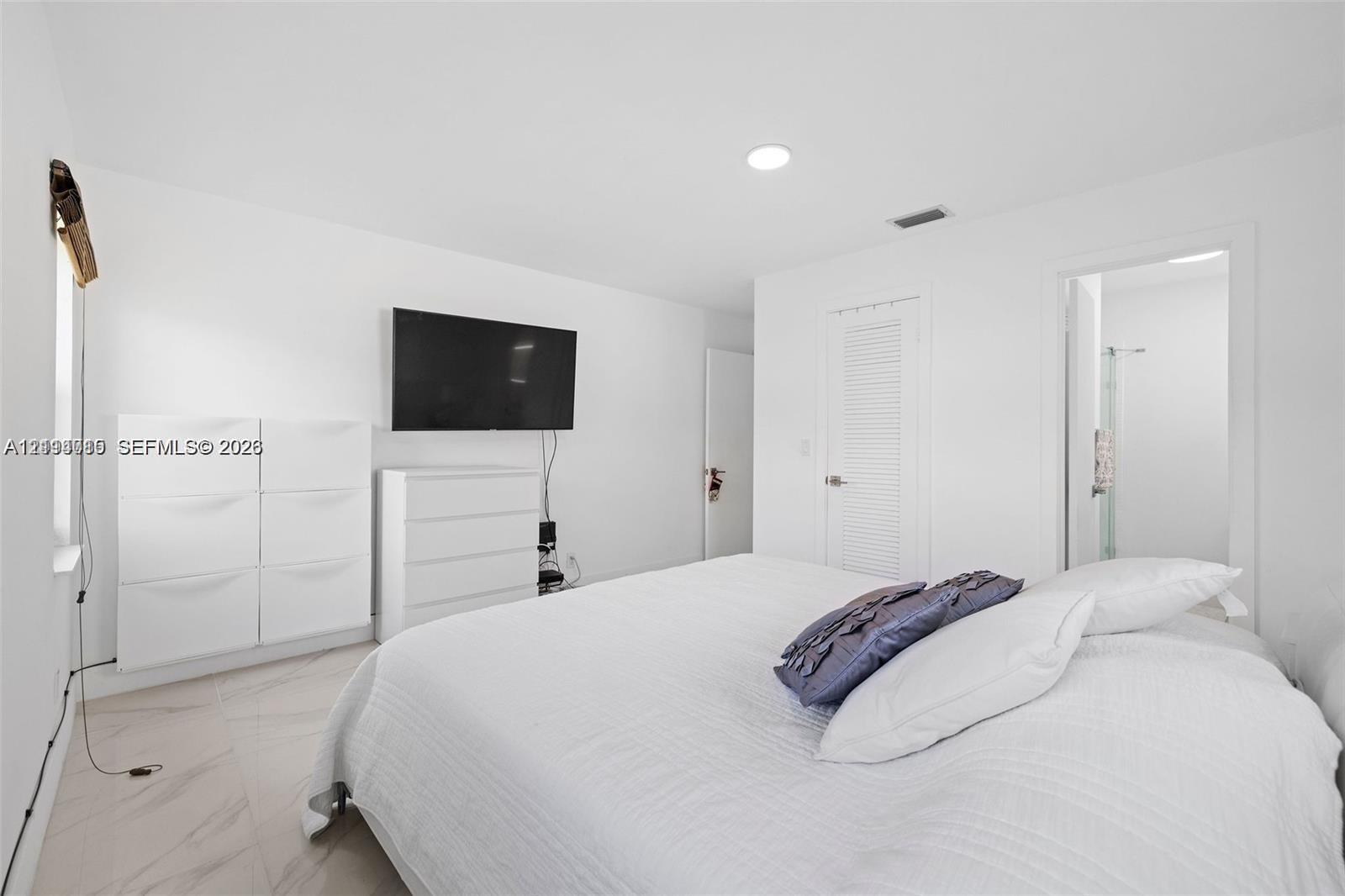 Interior space featuring large-format tile flooring, recessed ceiling lighting, and a louvered closet door