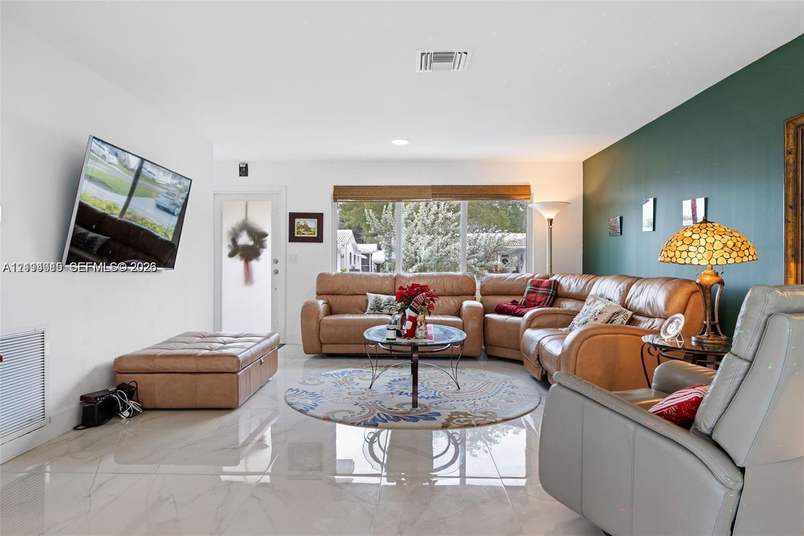 Large-format polished tile flooring, deep-toned accent wall, and expansive window with integrated window shade