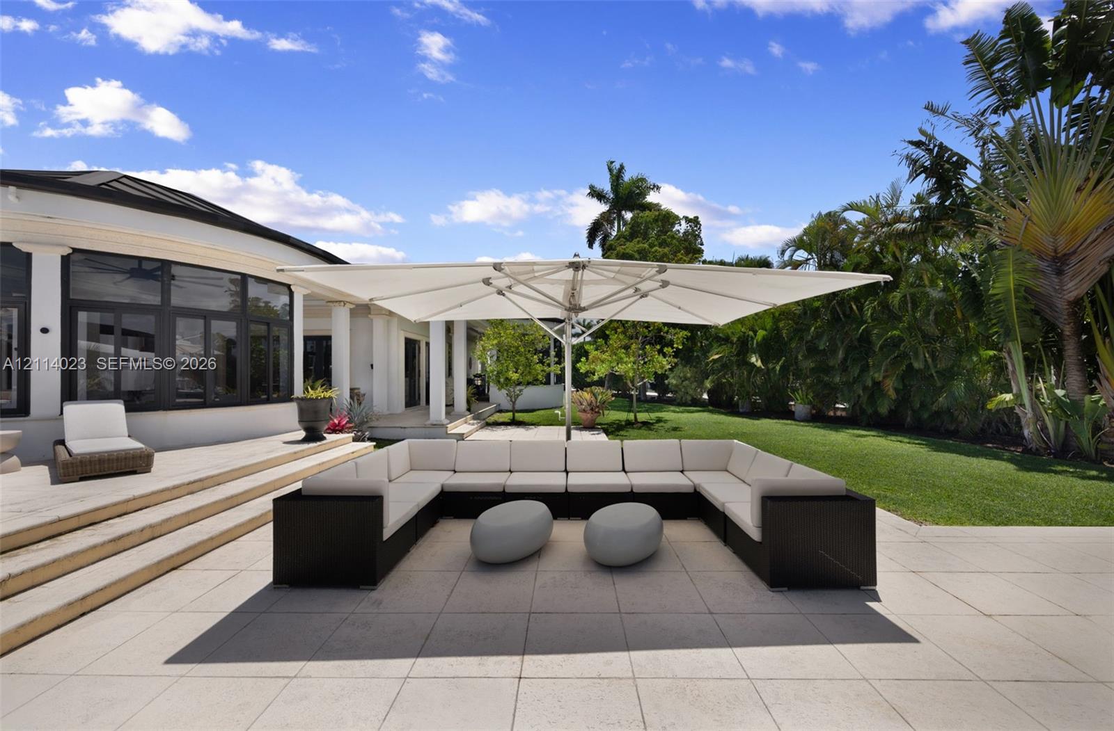 Expansive stone-paved patio featuring multi-tiered steps, large-format tile surfaces, and a perimeter of mature landscaping