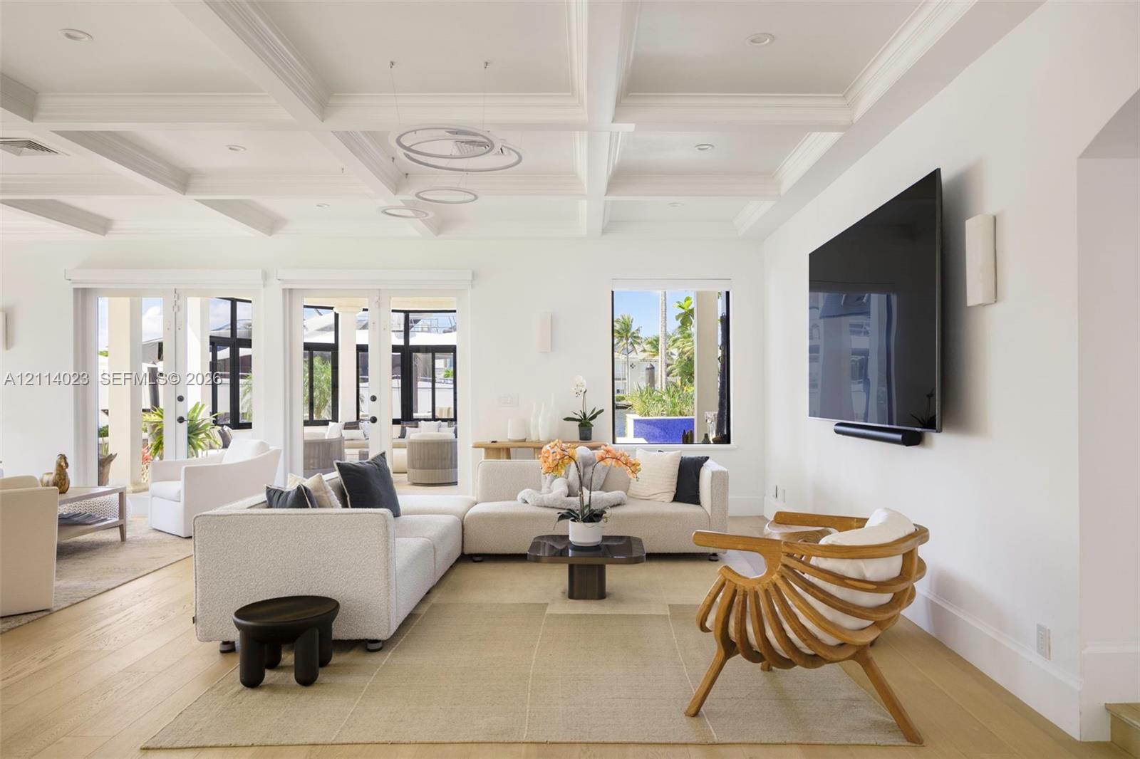 Coffered ceilings, recessed lighting, wood-finish flooring, and multiple sets of glass-paneled double doors