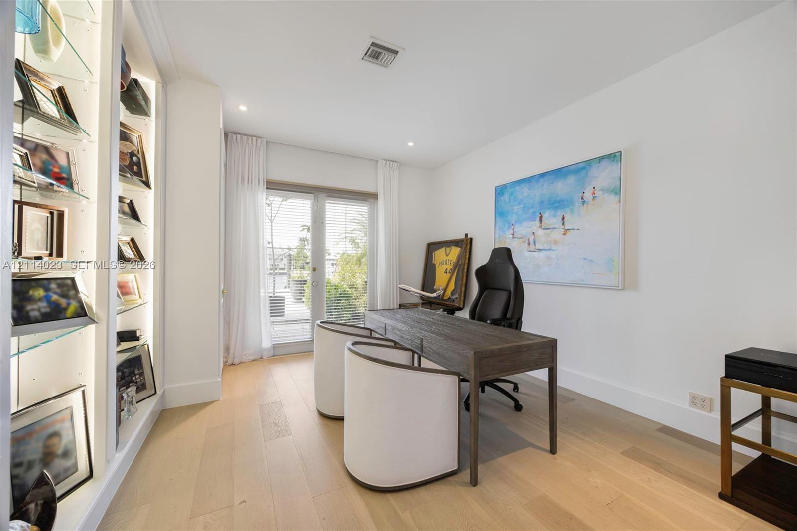 Built-in floor-to-ceiling display shelving with glass-paneled levels, recessed lighting, wood-finish flooring, and glass-paned double doors with exterior access