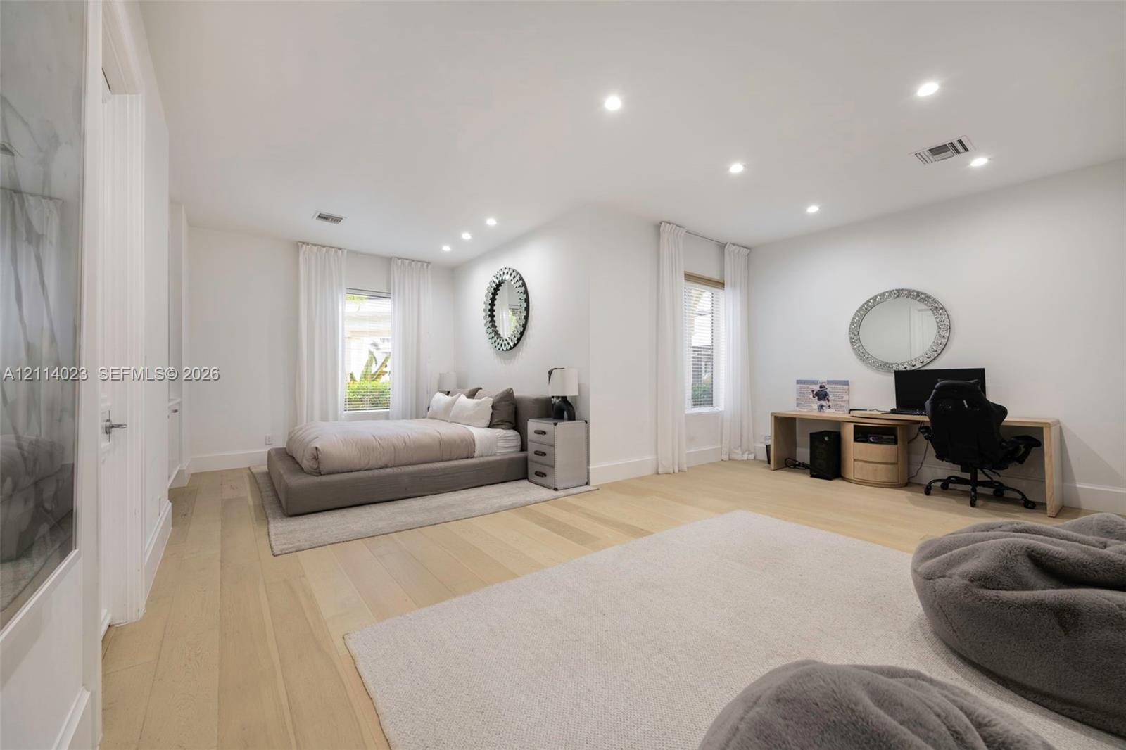 Spacious room featuring wood-finish flooring, recessed lighting, and multiple windows