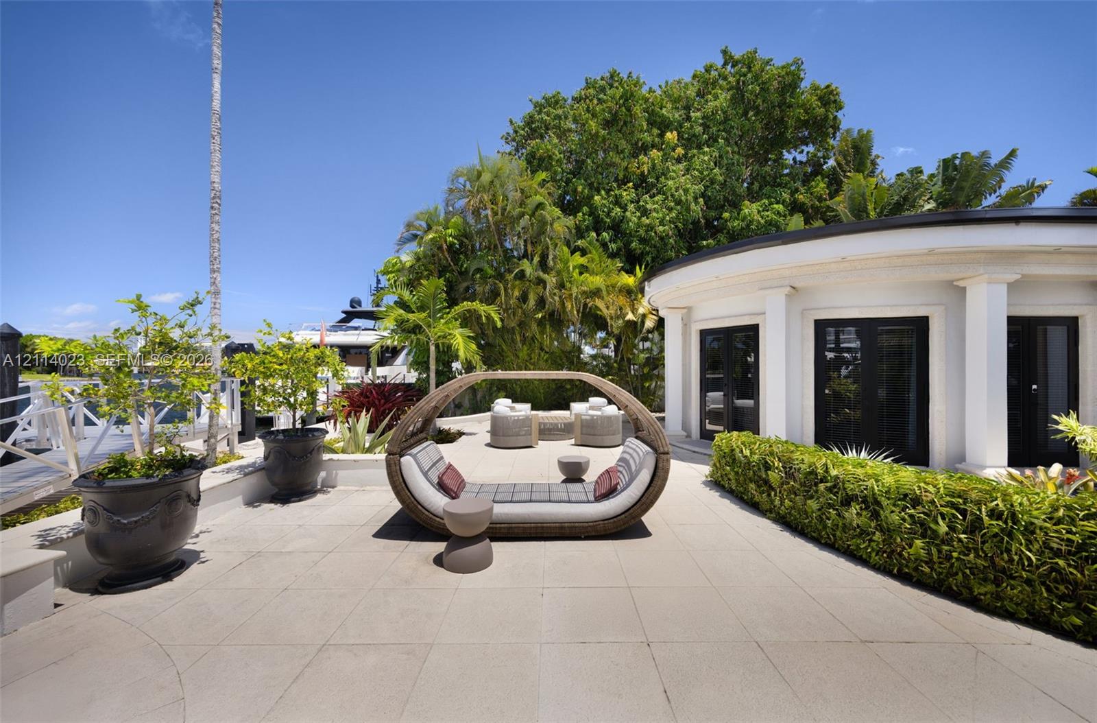 Waterfront terrace featuring stone paving, structural columns, built-in landscaping, and multiple access points with dark-framed doors