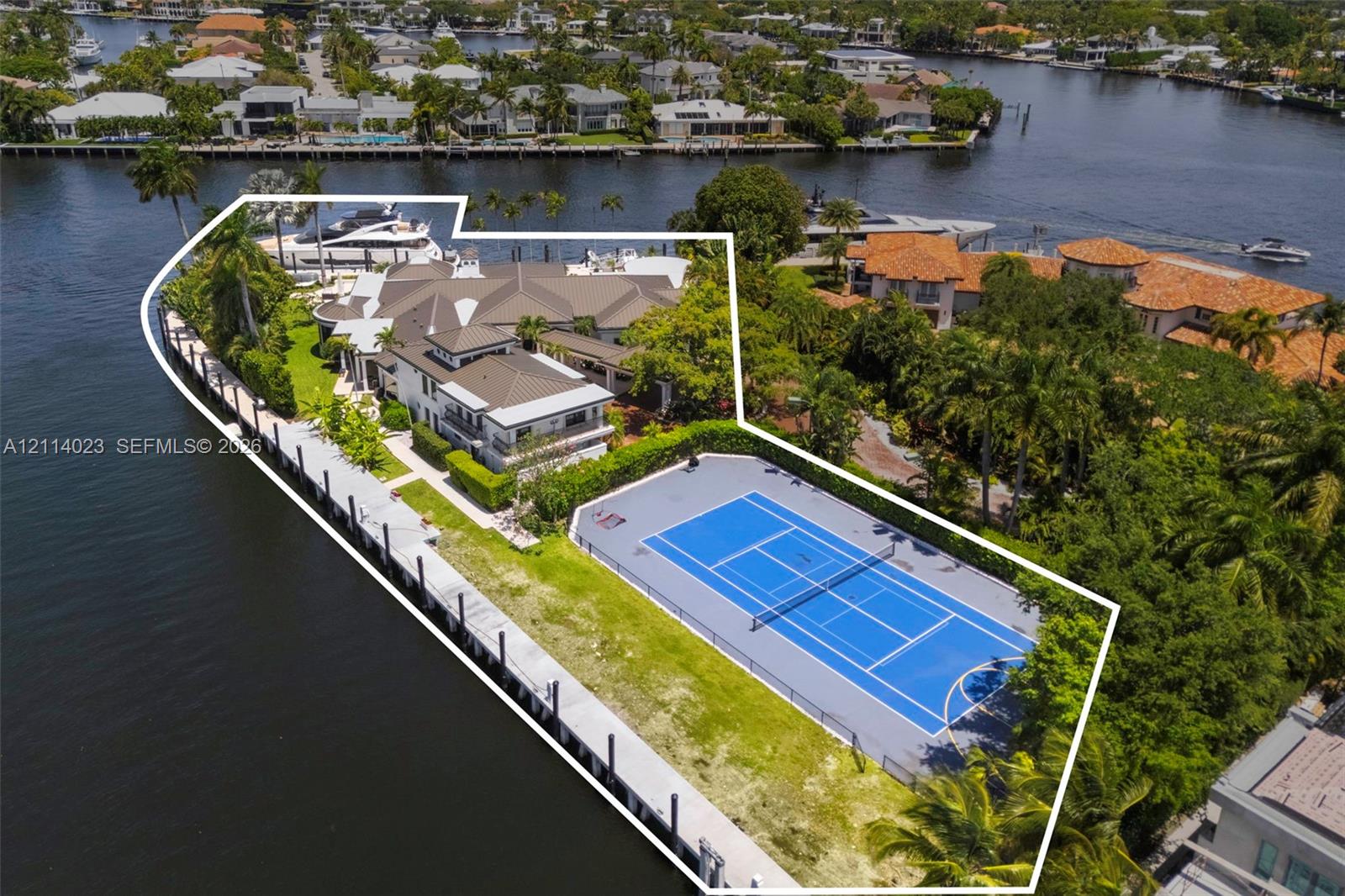 Waterfront estate featuring a private tennis court, expansive bulkhead dockage, multi-level residence with a multi-hipped roof, and mature perimeter landscaping Waterfront estate featuring a private tennis court, expansive bulkhead dockage, multi-level residence with a multi-hipped roof, and mature perimeter landscaping