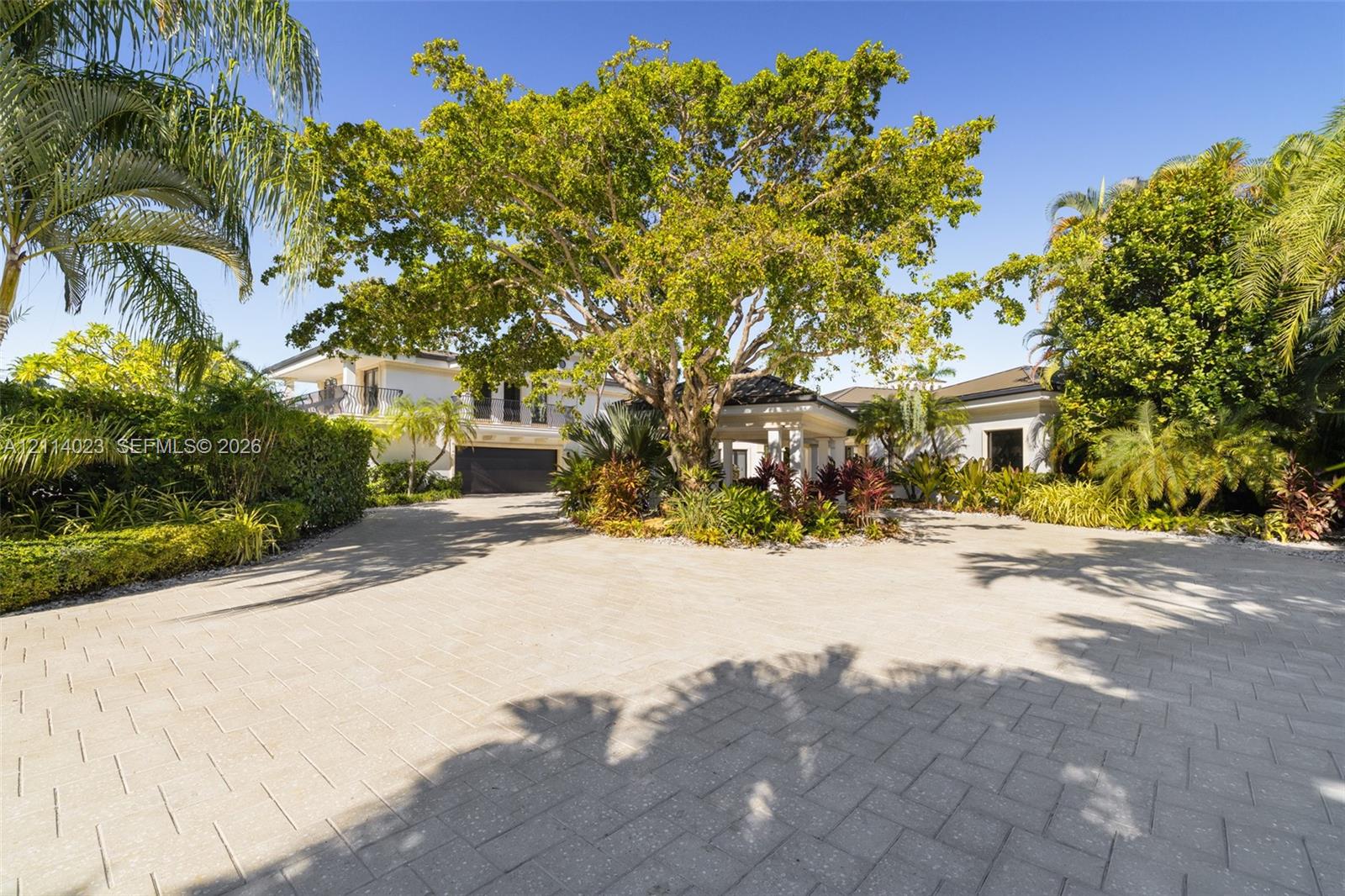 Paver driveway leading to a covered entryway, mature specimen trees, and established perimeter landscaping Paver driveway leading to a covered entryway, mature specimen trees, and established perimeter landscaping
