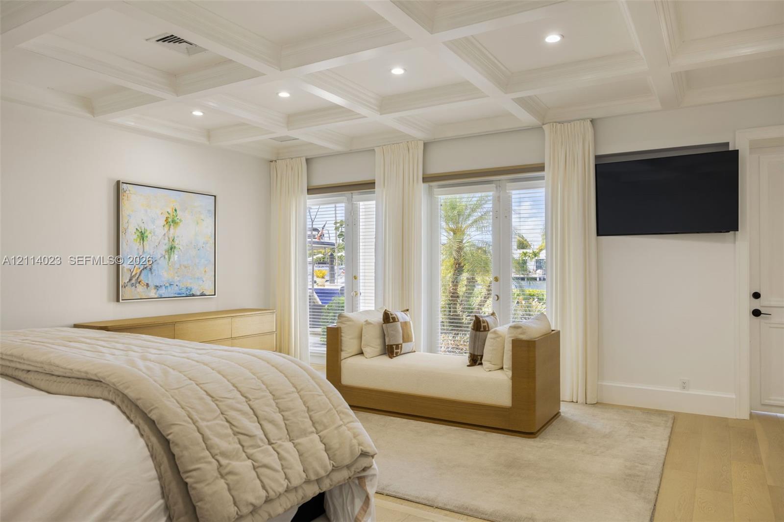 Coffered ceiling with recessed lighting, double French doors, and wood-finish flooring