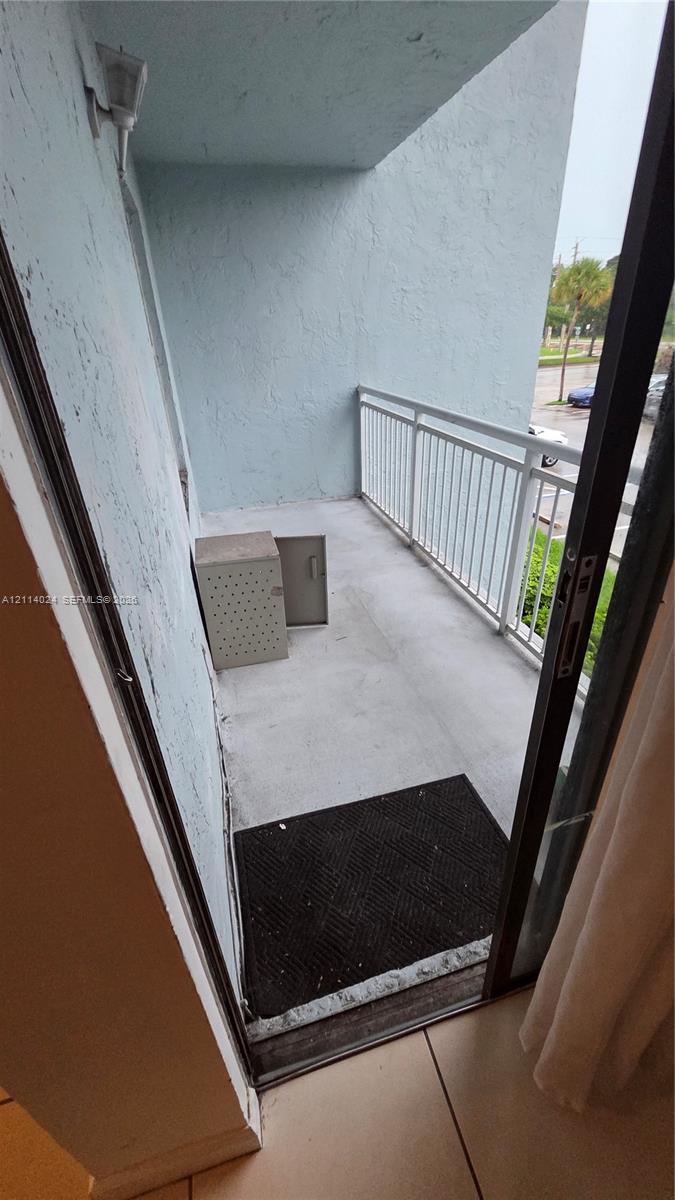 Covered balcony featuring concrete flooring and white metal railing Covered balcony featuring concrete flooring and white metal railing