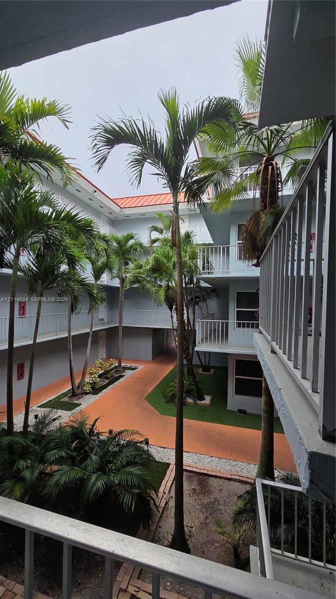 Central courtyard featuring palm trees, tiered balconies with metal railings, a paved walkway, and maintained greenery Central courtyard featuring palm trees, tiered balconies with metal railings, a paved walkway, and maintained greenery