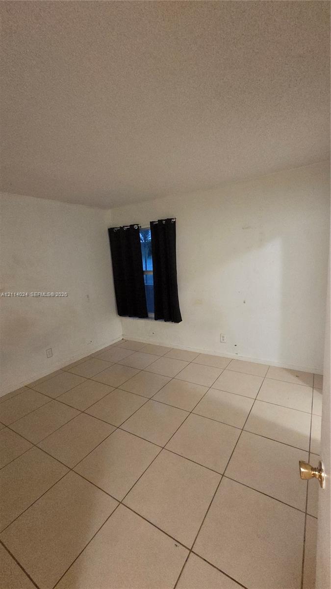 Interior space featuring large-format neutral tile flooring and a single window with a dual-panel configuration Interior space featuring large-format neutral tile flooring and a single window with a dual-panel configuration