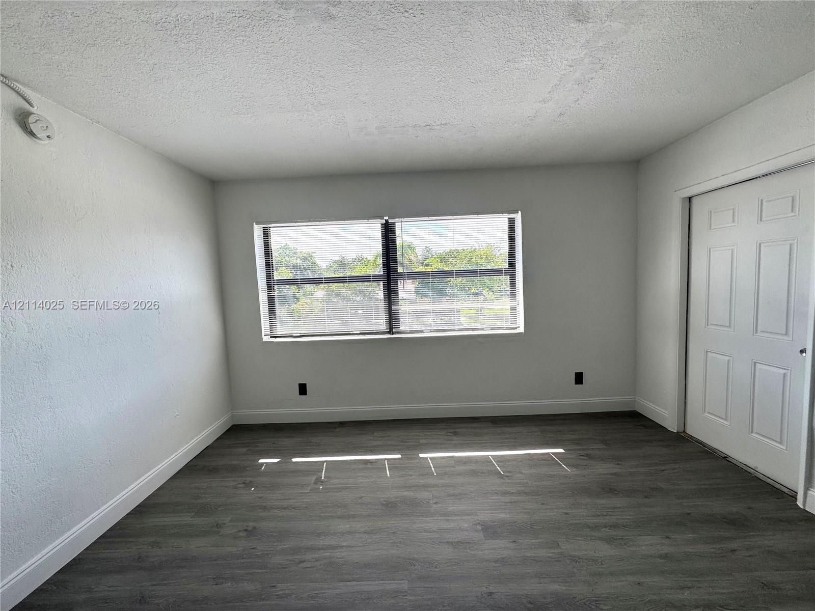 Interior room featuring neutral wall finishes, wood-finish flooring, a multi-pane window, and a six-panel door