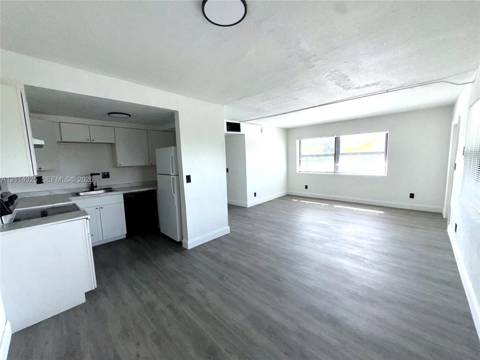 Kitchen featuring white cabinetry, wood-finish flooring, and a large window