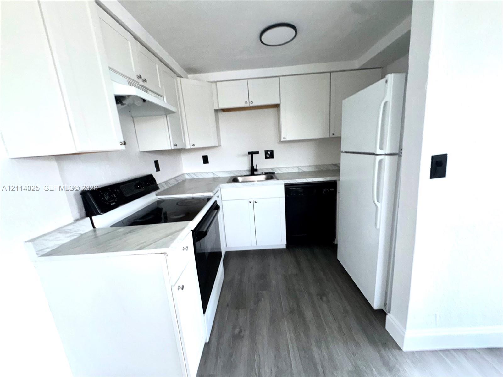 Kitchen featuring white cabinetry, wood-finish flooring, stone-pattern countertops, a stainless steel sink with a matte black faucet, and a black dishwasher