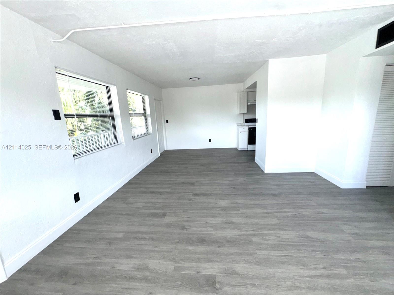 Open-concept interior featuring flooring, dual windows, and white cabinetry