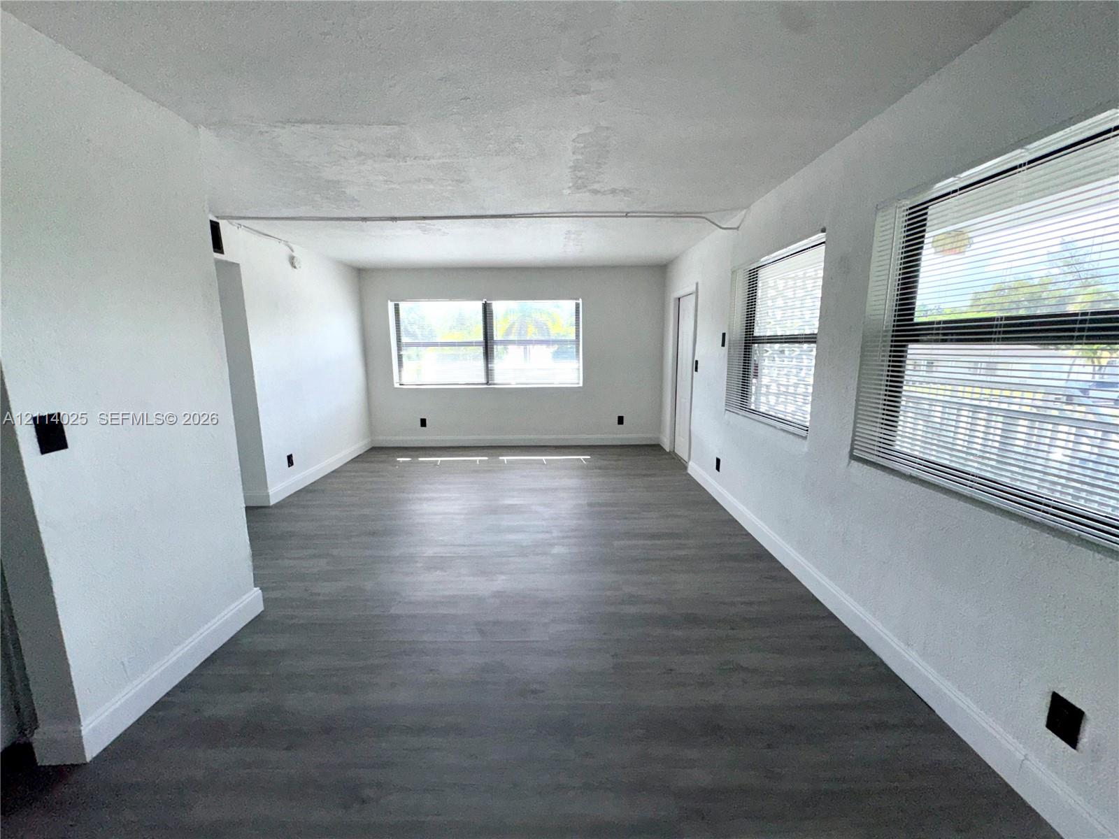 Neutral interior space featuring wood-finish flooring, multi-pane windows, and minimalist wall finishes