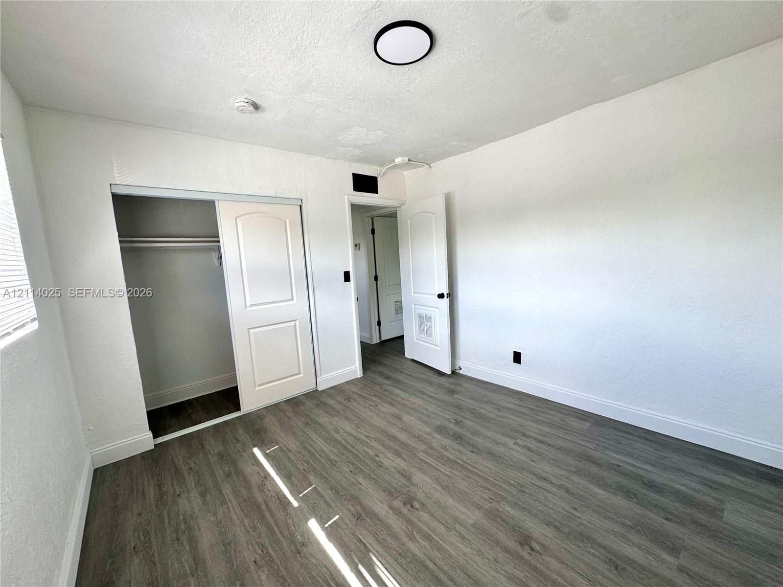 Room featuring wood-finish flooring, two-panel interior doors, a sliding closet door, and a flush-mount circular ceiling light