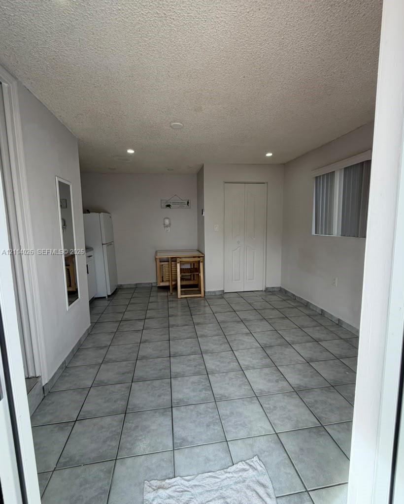 Large-format tile flooring, recessed ceiling lighting, and double-door closet with paneled detailing